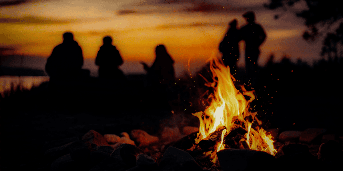 Campfire with people at sunset on Cumberland Flux outdoor adventure site.